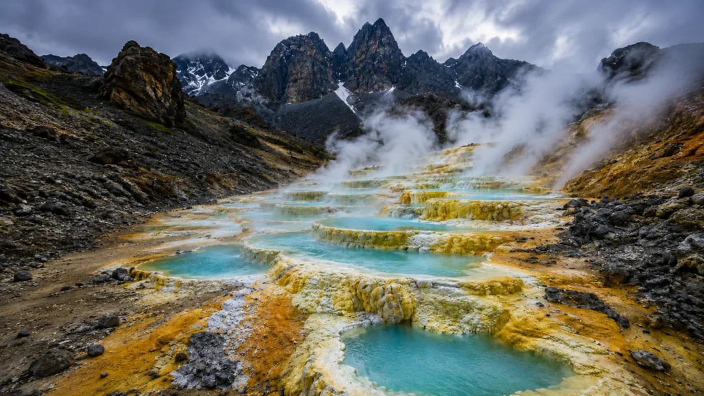 Natural geothermal hot springs surrounded by steaming volcanic mountains in Iceland.