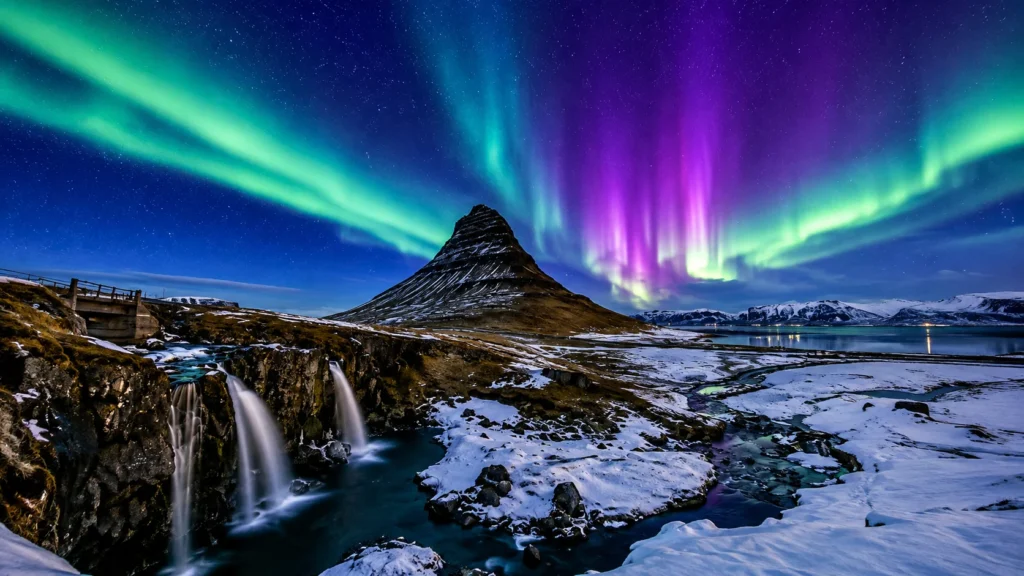 Northern Lights dancing above Kirkjufell Mountain and Kirkjufellsfoss waterfall in Iceland.