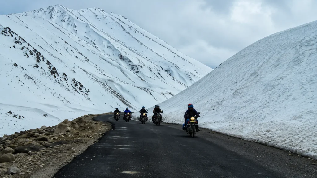 Bikers riding through snow-covered mountains during a Ladakh Road Trip Guide adventure